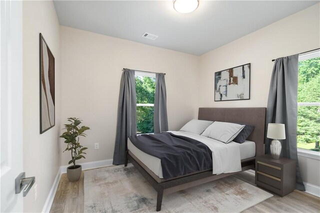 bedroom with multiple windows and light wood-type flooring