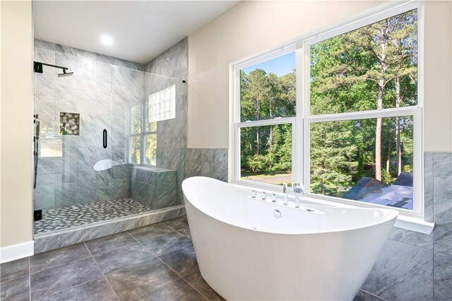 bathroom featuring shower with separate bathtub, tile walls, and a wealth of natural light