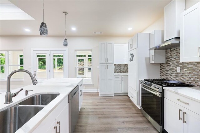 kitchen with white cabinetry, sink, hanging light fixtures, light stone counters, and stainless steel appliances