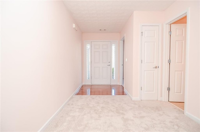 carpeted entryway with baseboards, visible vents, and a textured ceiling