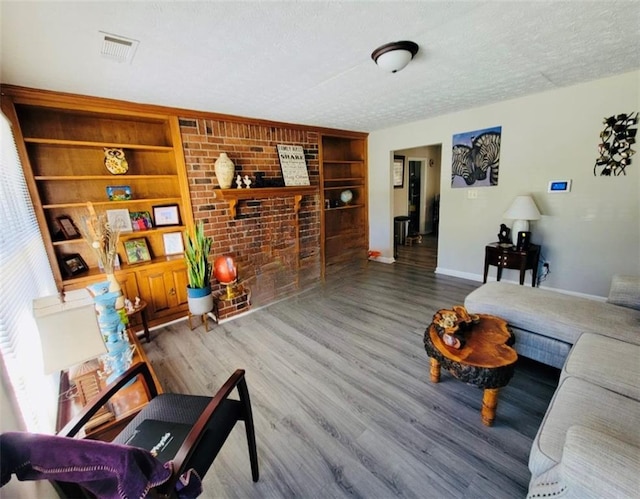 living room featuring hardwood / wood-style flooring, built in features, and a textured ceiling