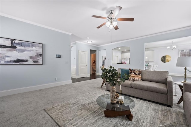 carpeted living room featuring ceiling fan with notable chandelier, baseboards, arched walkways, and ornamental molding