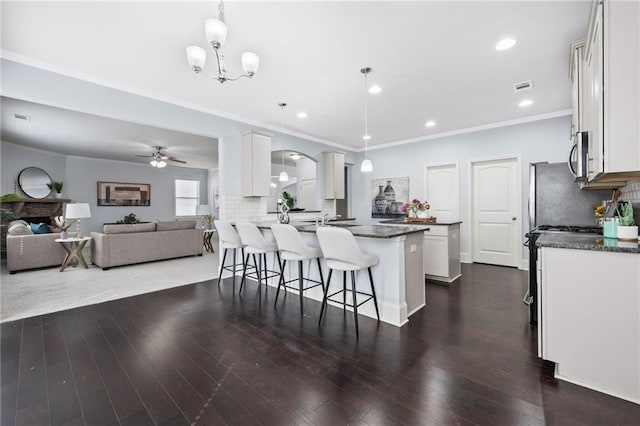 kitchen featuring tasteful backsplash, stainless steel microwave, a kitchen breakfast bar, dark wood-style flooring, and a peninsula