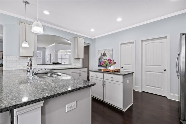 kitchen featuring decorative backsplash, dark wood finished floors, a kitchen island, crown molding, and a sink