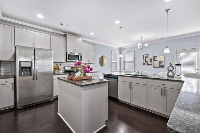 kitchen featuring appliances with stainless steel finishes, a center island, crown molding, and a sink