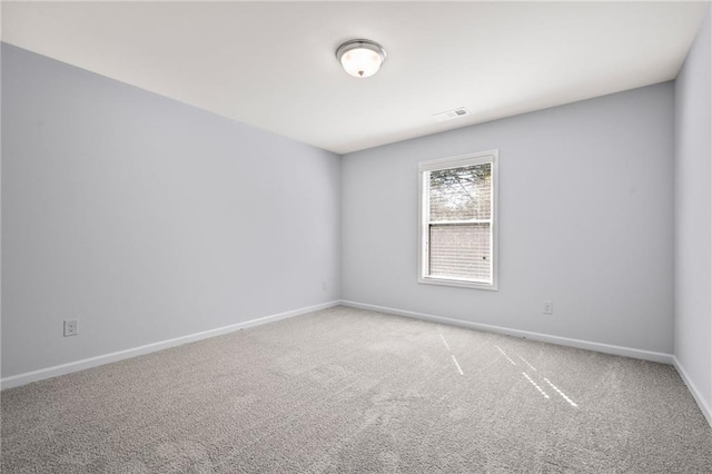 spare room featuring carpet, visible vents, and baseboards