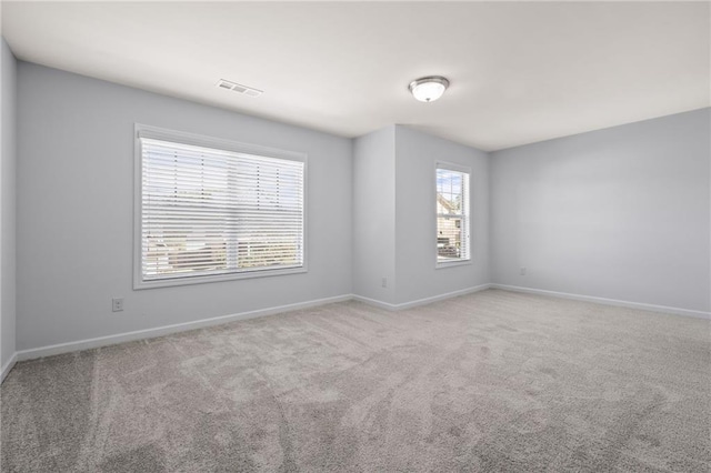 spare room with carpet floors, visible vents, and baseboards