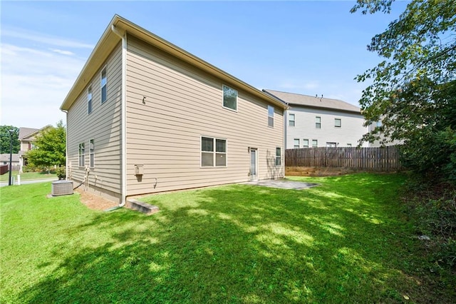 rear view of house with a patio, a lawn, cooling unit, and fence