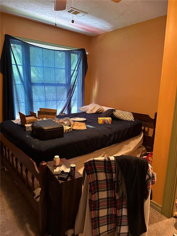 bedroom featuring a textured ceiling and light colored carpet