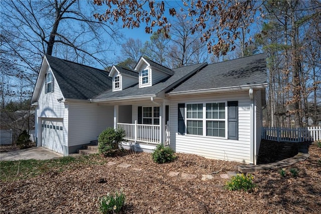 cape cod-style house with a shingled roof, covered porch, concrete driveway, and fence