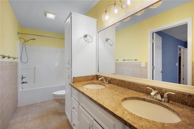 bathroom featuring tile patterned flooring, tile walls, toilet, and a sink