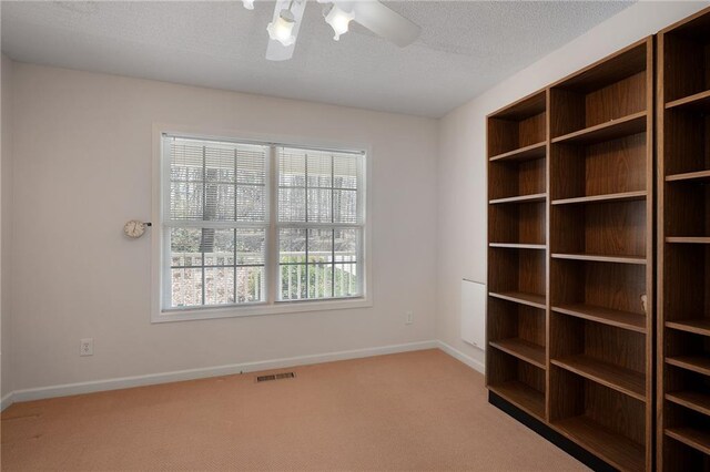 carpeted empty room with ceiling fan, baseboards, visible vents, and a textured ceiling