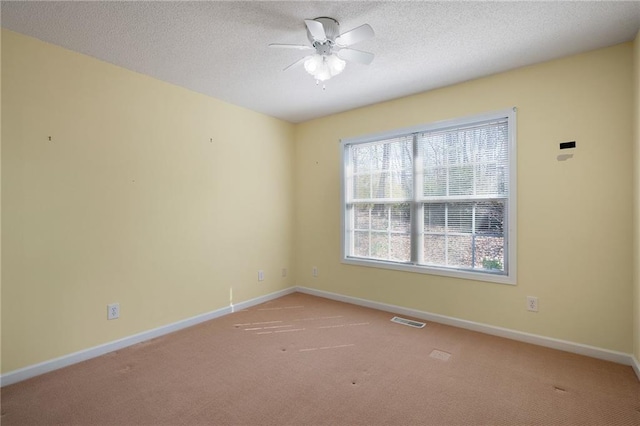 carpeted empty room featuring visible vents, baseboards, a textured ceiling, and ceiling fan