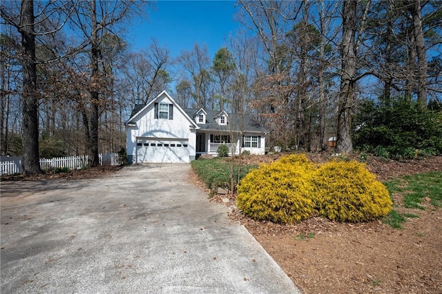 cape cod-style house featuring fence, a garage, and driveway