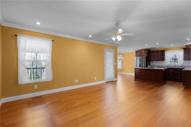 kitchen with visible vents, ornamental molding, a center island, stainless steel fridge, and light wood finished floors