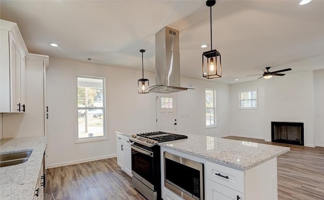 kitchen featuring appliances with stainless steel finishes, island range hood, white cabinets, and a kitchen island