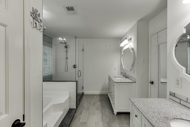 4690 Martins Crossing W Dr, Flowery Branch, GA 30542 - bathroom featuring two vanities, a shower stall, a garden tub, wood finished floors, and baseboards