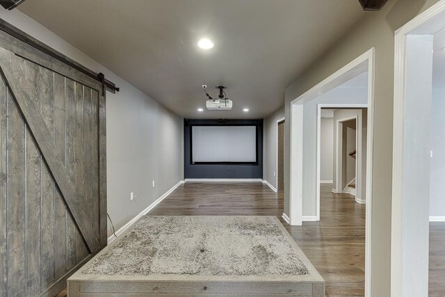 4690 Martins Crossing W Dr, Flowery Branch, GA 30542 - cinema room featuring a barn door, wood finished floors, baseboards, and recessed lighting