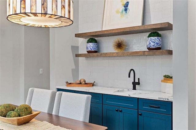 bar featuring tasteful backsplash, blue cabinets, sink, and light stone counters