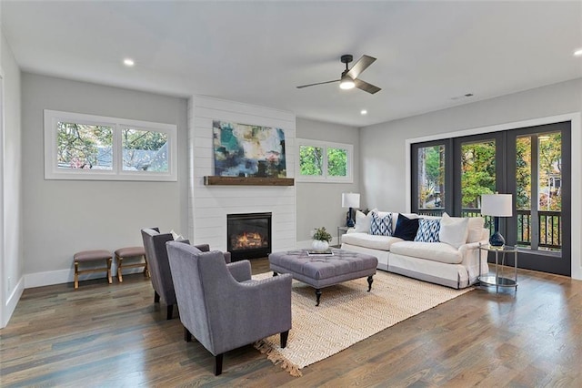 living room featuring ceiling fan, a fireplace, and dark hardwood / wood-style flooring