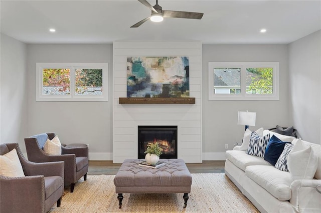 living room with ceiling fan, a large fireplace, and light hardwood / wood-style floors