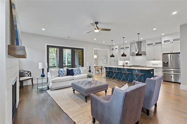 living room with wood-type flooring, sink, and ceiling fan