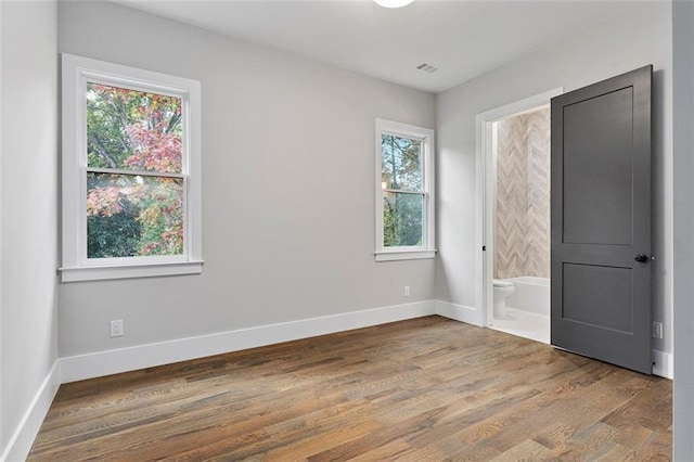 660 Timm Valley Rd NE, Atlanta, GA 30305 - unfurnished bedroom with baseboards, visible vents, wood finished floors, and ensuite bath