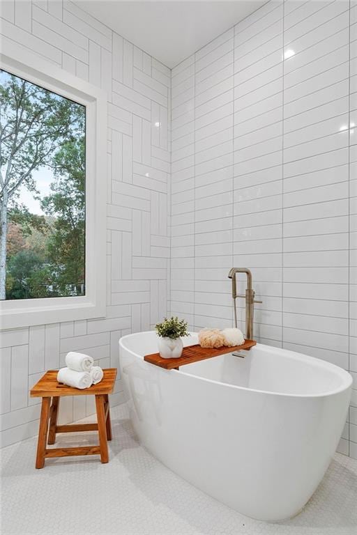 bathroom featuring tile patterned flooring, a tub, and tile walls