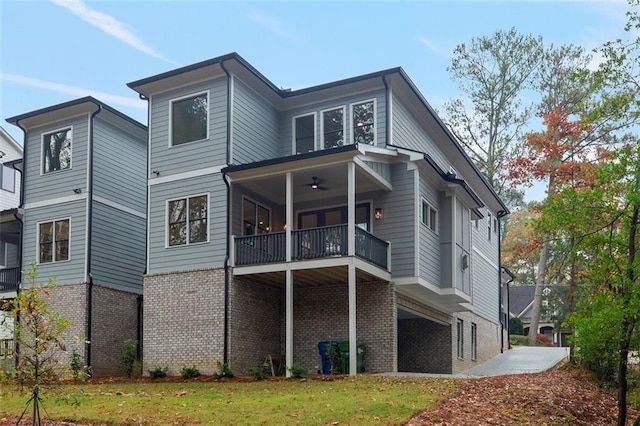 rear view of house with a lawn, a balcony, and ceiling fan