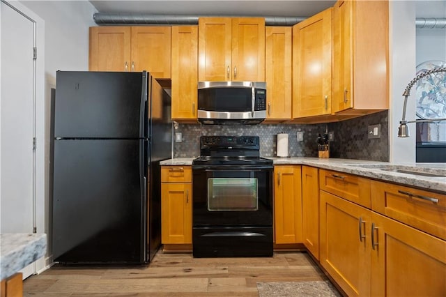 800 Peachtree St NE Unit 1504, Atlanta, GA 30308 - kitchen featuring black appliances, light wood finished floors, decorative backsplash, and light stone countertops