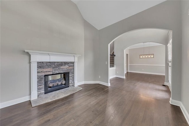420 Gold Xing, Canton, GA 30114 - unfurnished living room with wood finished floors, a stone fireplace, high vaulted ceiling, and arched walkways