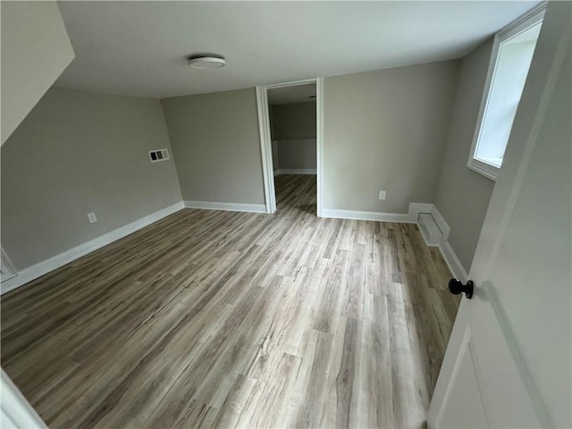 unfurnished bedroom with baseboards, a spacious closet, visible vents, and wood finished floors