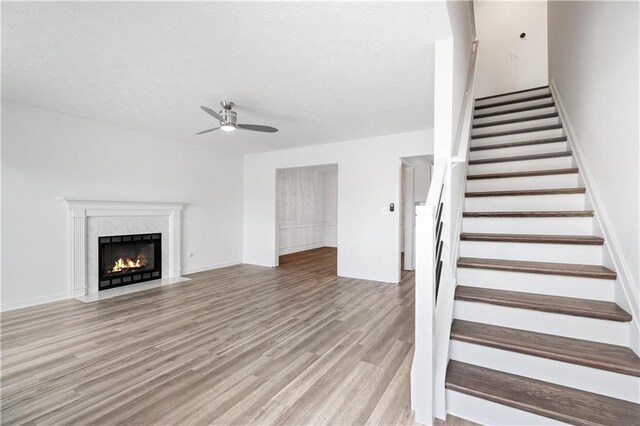 unfurnished living room featuring a premium fireplace, light hardwood / wood-style floors, and ceiling fan