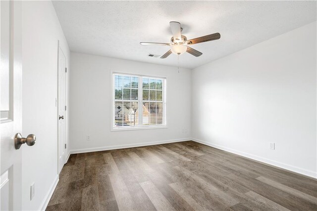 spare room with a textured ceiling, dark wood-type flooring, and ceiling fan