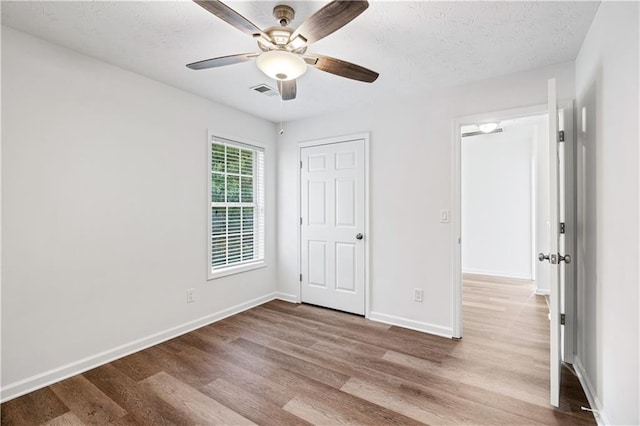 unfurnished bedroom featuring ceiling fan, a textured ceiling, and light wood-type flooring