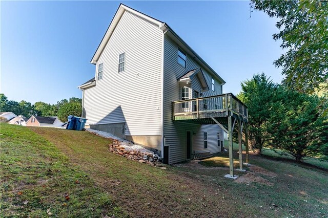 rear view of property featuring a deck and a lawn