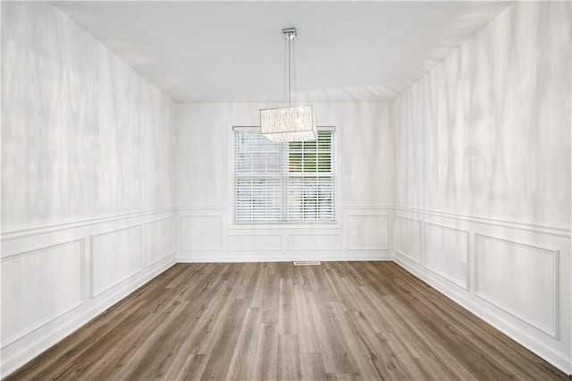 unfurnished dining area featuring a notable chandelier and wood-type flooring