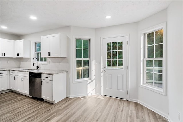 kitchen featuring light stone counters, sink, white cabinetry, dishwasher, and light wood-type flooring