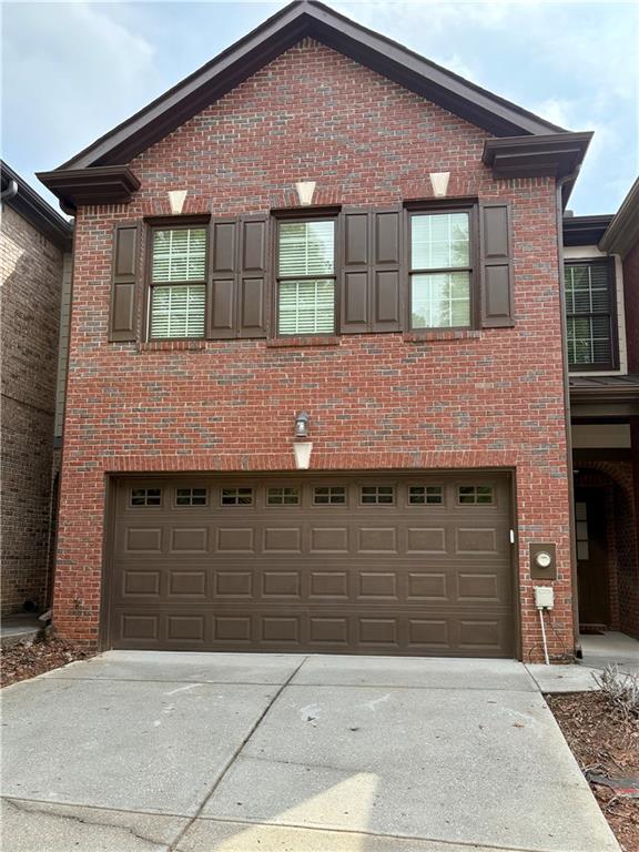 view of front of home featuring driveway, brick siding, and an attached garage