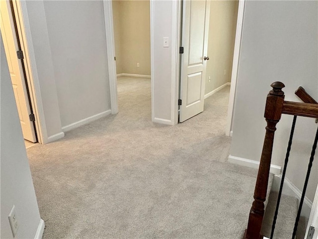 corridor with baseboards, an upstairs landing, and carpet