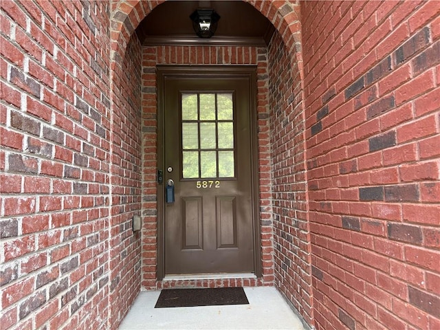 doorway to property featuring brick siding