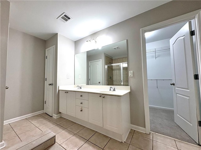 full bathroom featuring tile patterned flooring, a shower stall, a sink, baseboards, and visible vents
