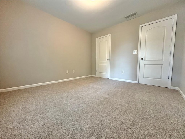 carpeted empty room featuring visible vents and baseboards