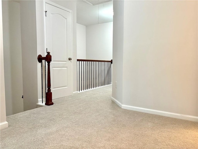 hall featuring baseboards, attic access, and carpet flooring