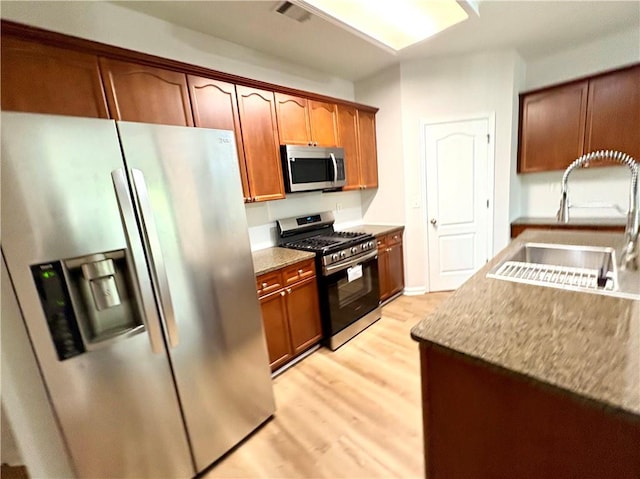 kitchen with a sink, visible vents, light wood-style flooring, light countertops, and appliances with stainless steel finishes