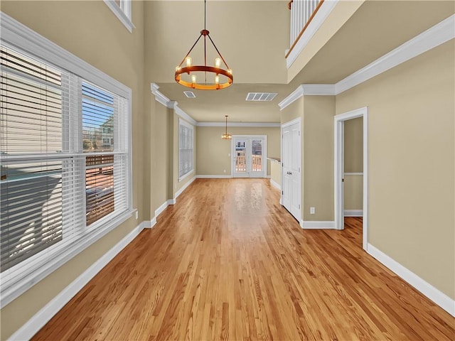 interior space with baseboards, visible vents, light wood finished floors, ornamental molding, and a chandelier