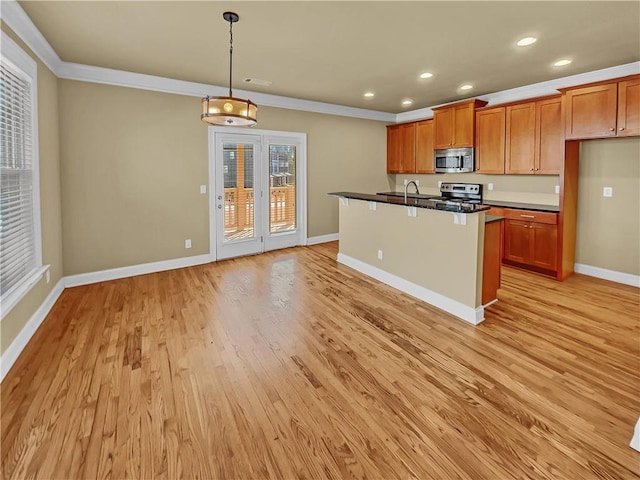 kitchen with dark countertops, appliances with stainless steel finishes, brown cabinetry, light wood finished floors, and baseboards