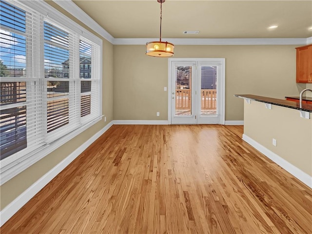 unfurnished dining area featuring visible vents, baseboards, light wood-style floors, and crown molding