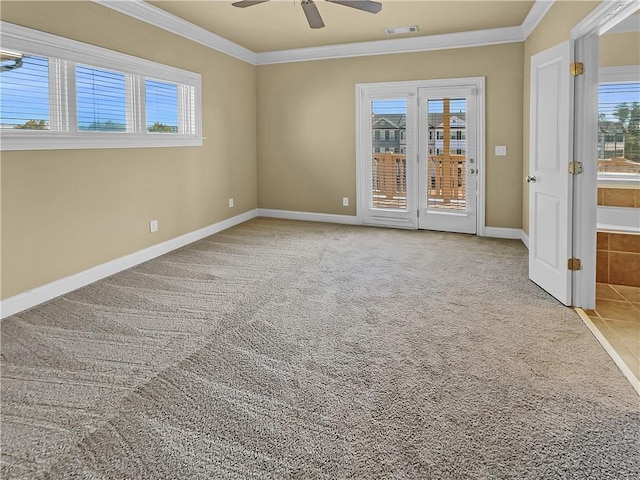 carpeted spare room featuring crown molding, baseboards, visible vents, and ceiling fan