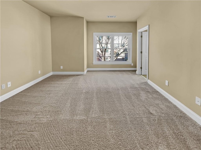 carpeted spare room with visible vents and baseboards